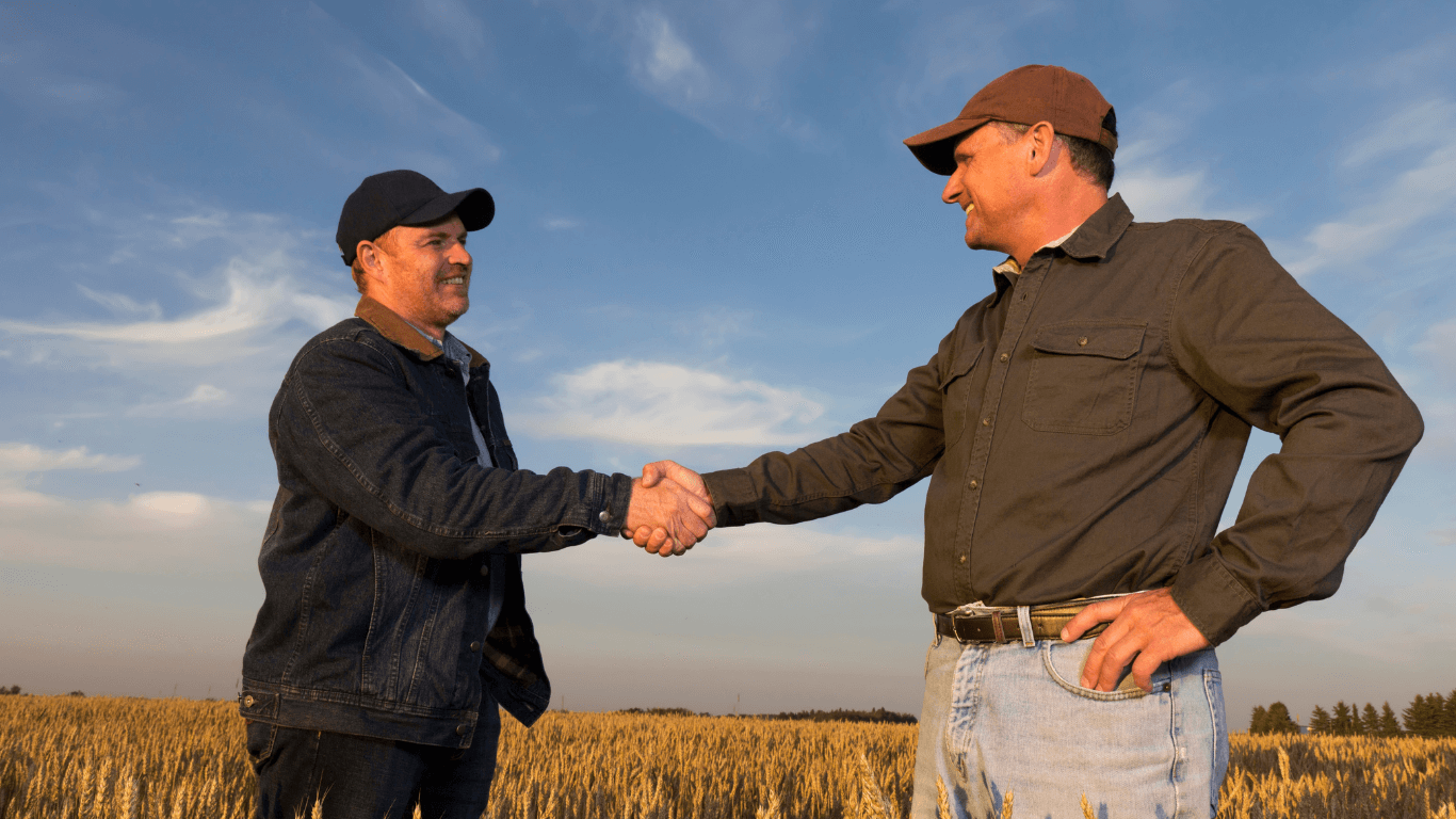 Two male farmers shaking hands.