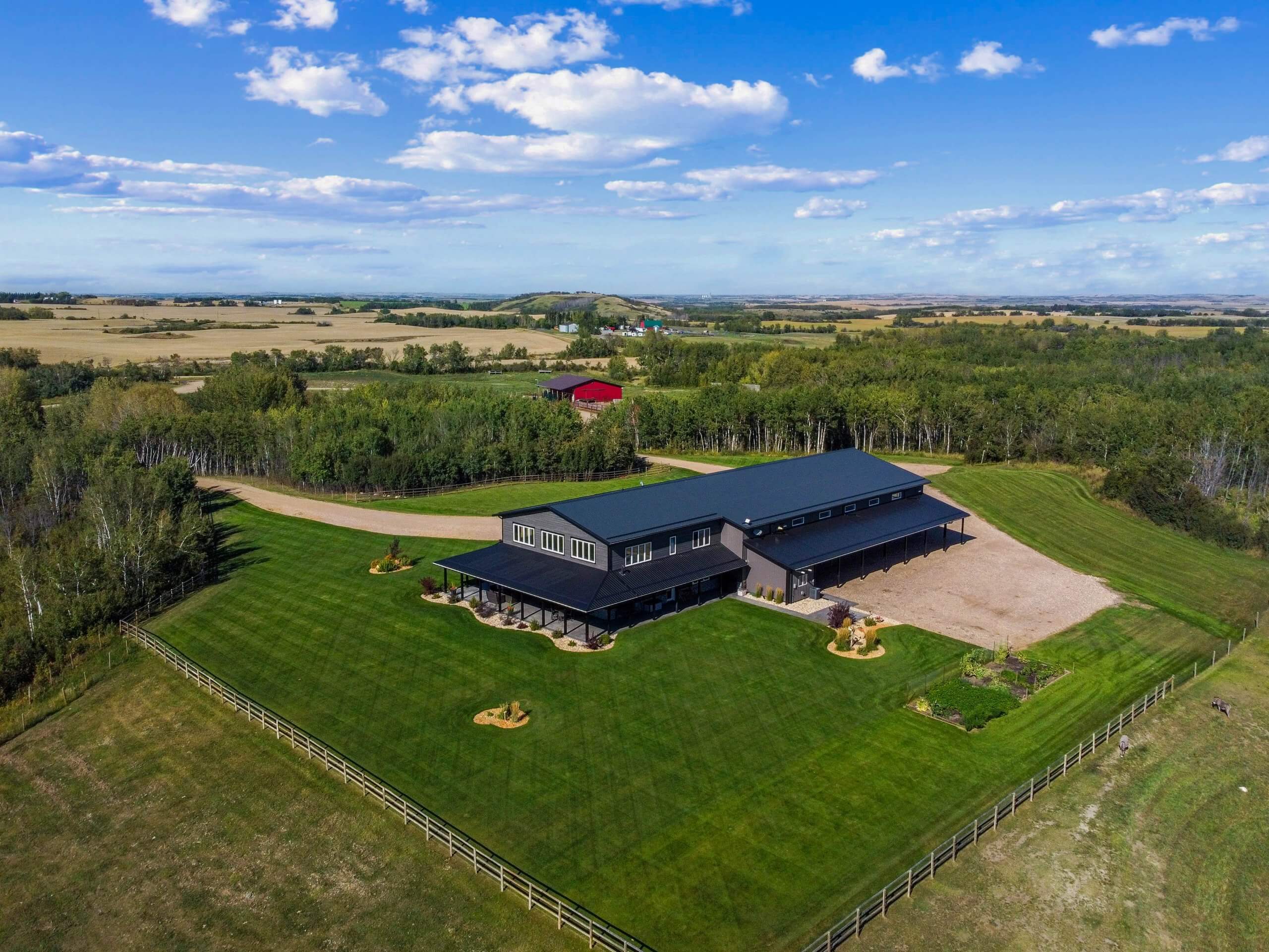 Aerial view of a modern executive home with a shop, situated on a vast, well-maintained quarter section surrounded by scenic countryside.